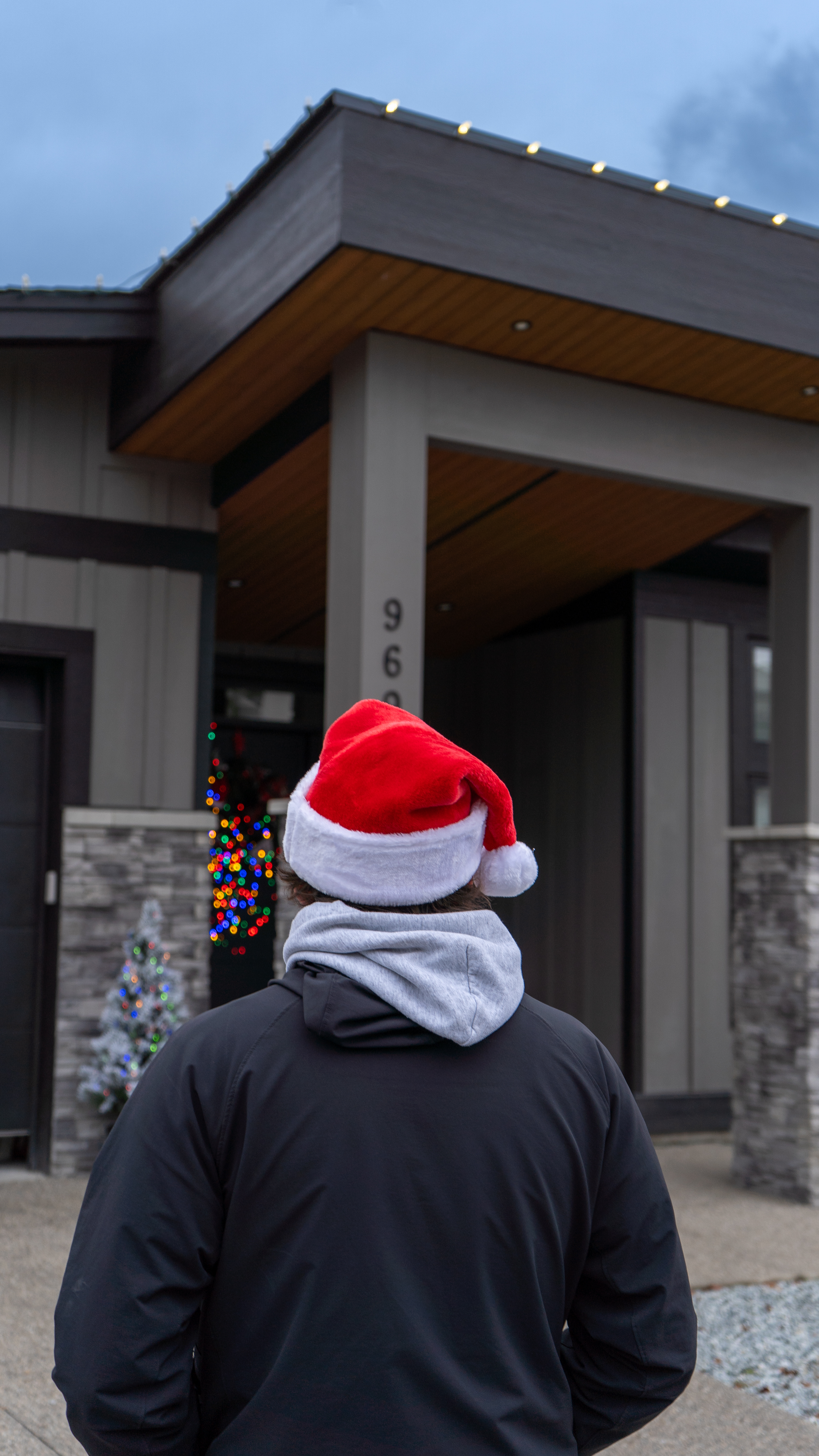Technician in a Santa hat in front of a modern home
